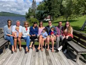 Family sitting on dock on lakeshore.